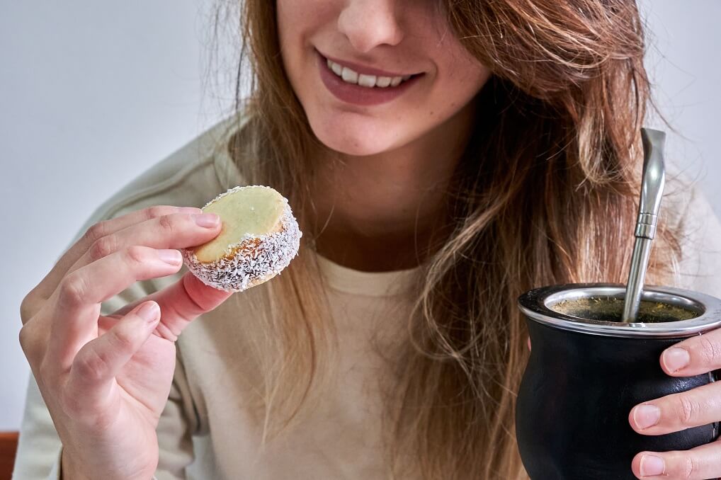Woman eating maize flour alfajor and drinking yerba mate infusion